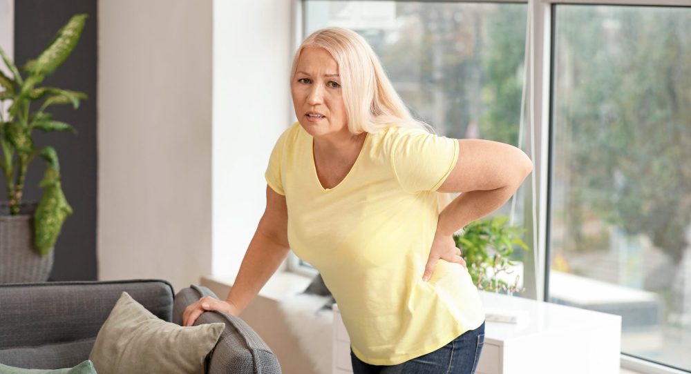 Mature woman suffering from back pain at home