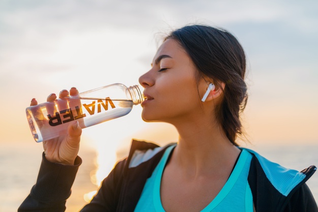 attractive-slim-woman-doing-sport-exercises-morning-sunrise-beach-sports-wear-thirsty-drinking-water-bottle-healthy-lifestyle-listening-music-wireless-earphones-smiling-happy_285396-5555